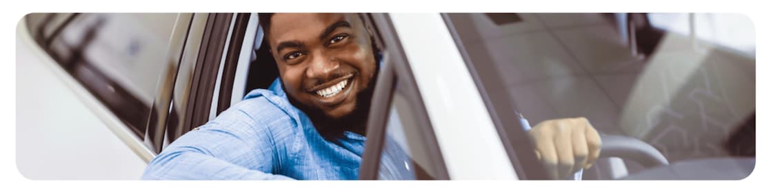 Un automobiliste souriant, satisfait des performances des huiles moteur Shell Helix et des services proposés dans les boutiques Shell Select.