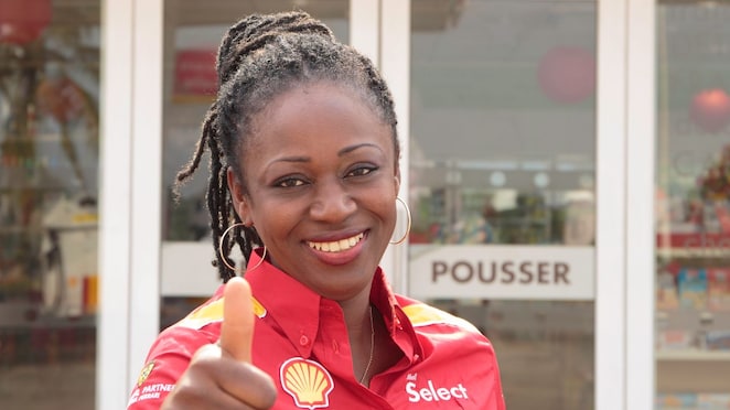 Femme souriante et accueillante devant une boutique Shell