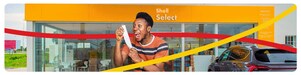 Client heureux devant une boutique Shell Select, tenant un ticket de jeux Lonaci et exprimant de la joie.