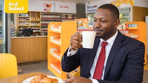 Un Homme tenant un Mug dans une boutique Shell Select".