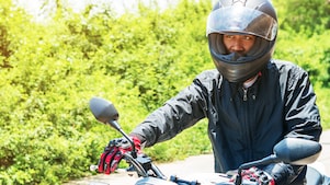 Un motocycliste équipé de tous les accessoires essentiels pour assurer sa sécurité à moto : casque homologué, blouson, gant