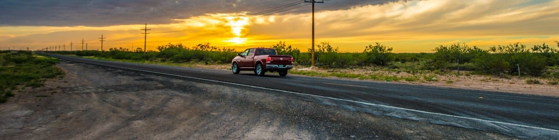Voiture qui roule au milieu d'un beau paysage dans le soleil couchant