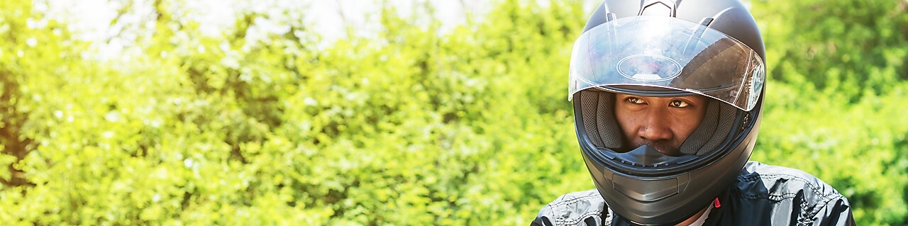 Un motocycliste équipé de tous les accessoires essentiels pour assurer sa sécurité à moto : casque homologué, blouson, gant