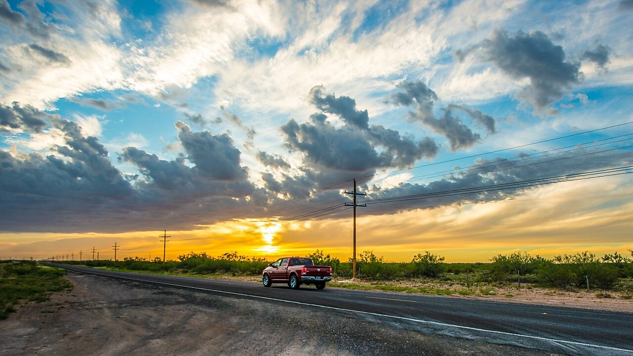Voiture qui roule au milieu d'un beau paysage dans le soleil couchant