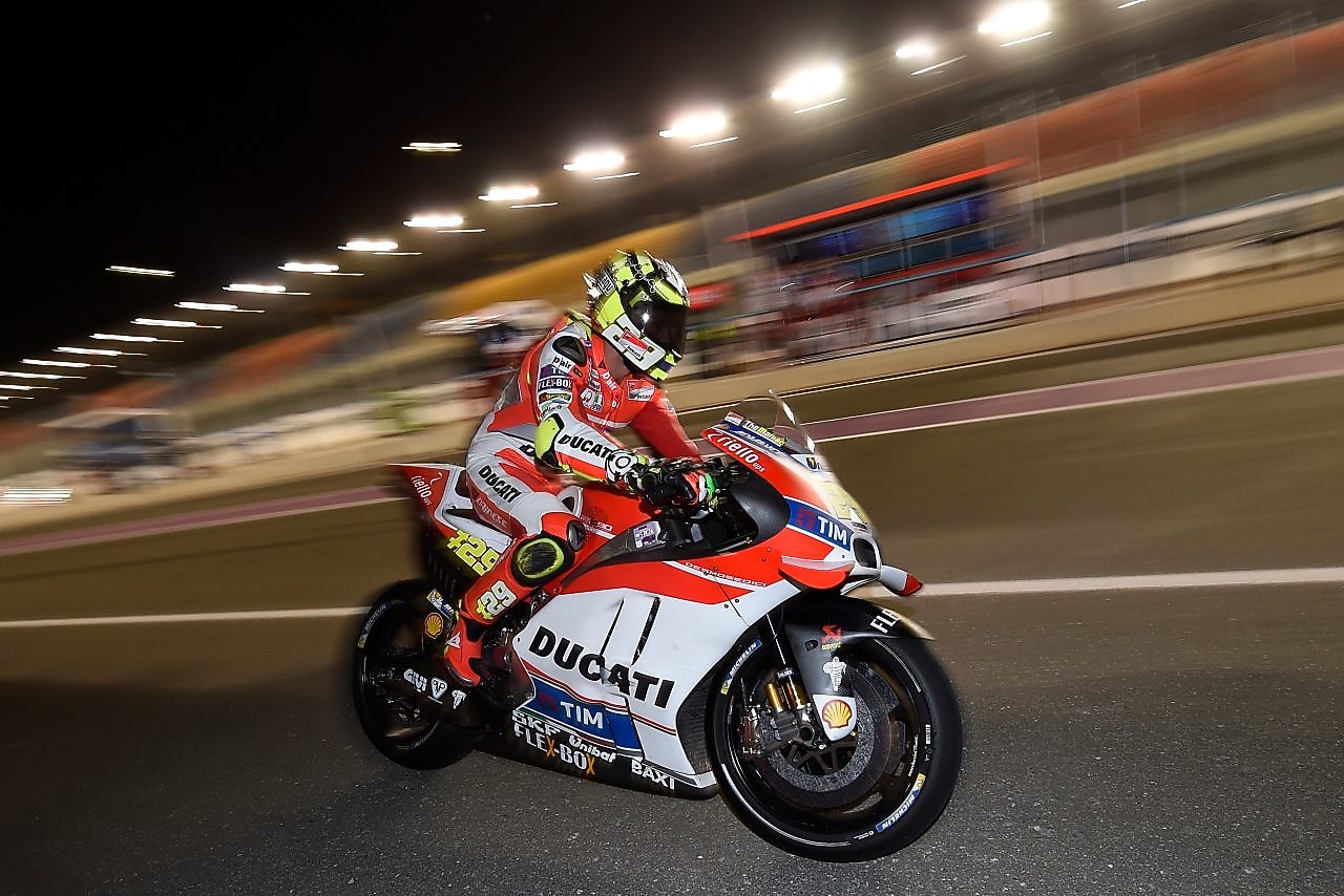 Pilote Ducati roulant vite sur une moto, sur un circuit, de nuit.