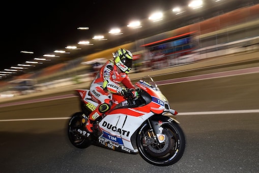 Pilote Ducati roulant vite sur une moto, sur un circuit, de nuit.
