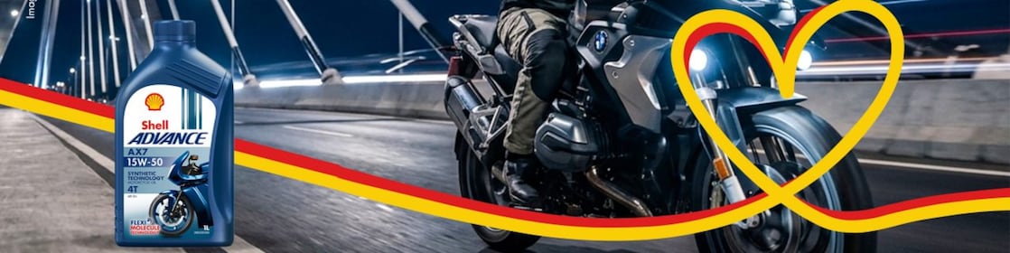 Motocycliste passant sur un pont avec bouteille Shell Advance AX7 en avant.