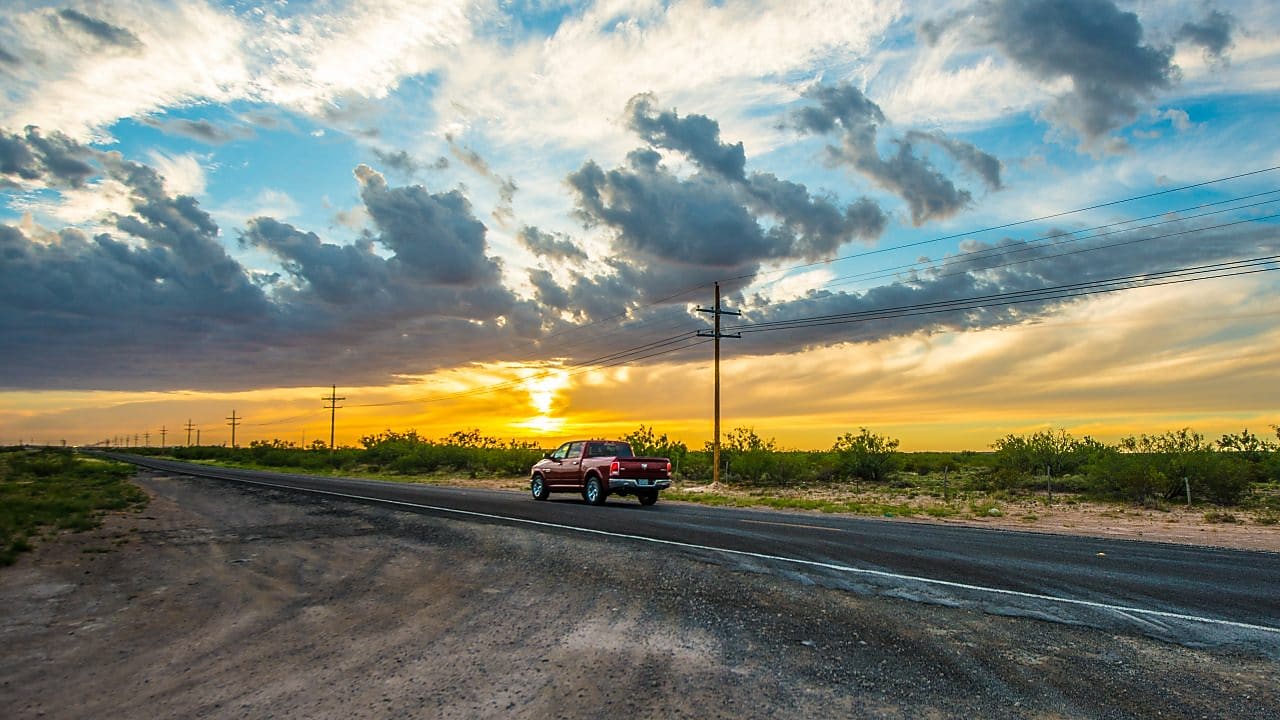 Voiture qui roule au milieu d'un beau paysage dans le soleil couchant