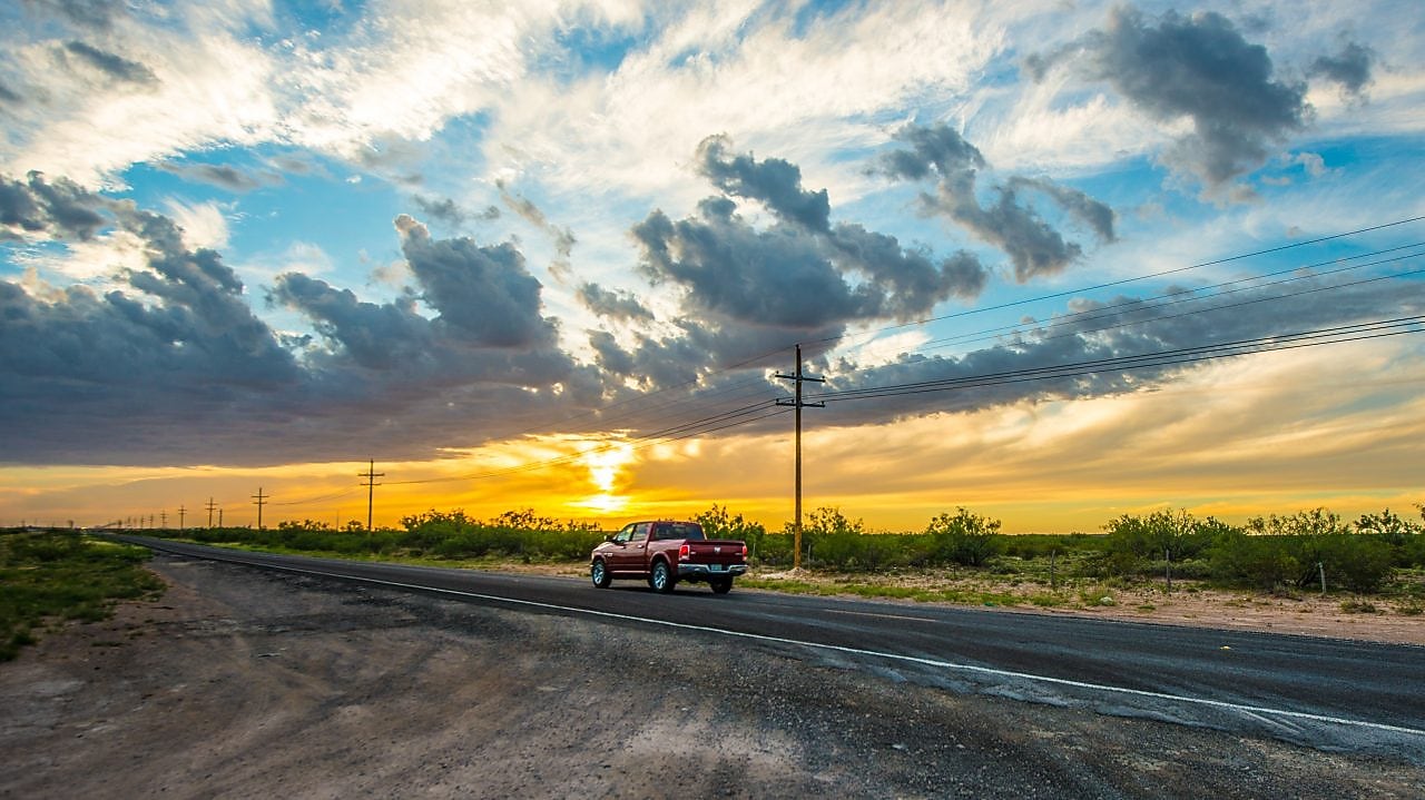 Voiture qui roule au milieu d'un beau paysage dans le soleil couchant